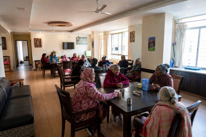 Residents sharing tea and conversation around tables in the dining hall
